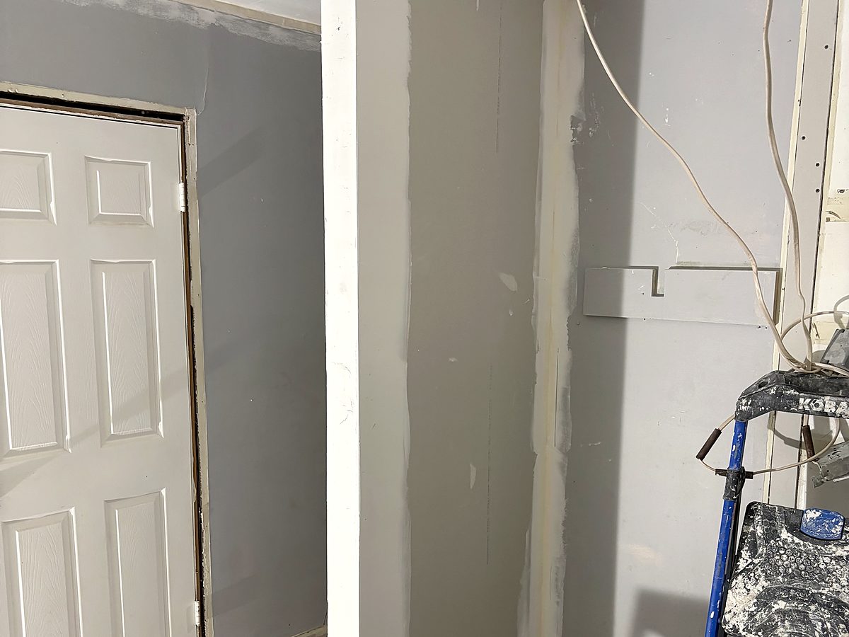 New drywall taped and mudded around a corner, before sanding and paint